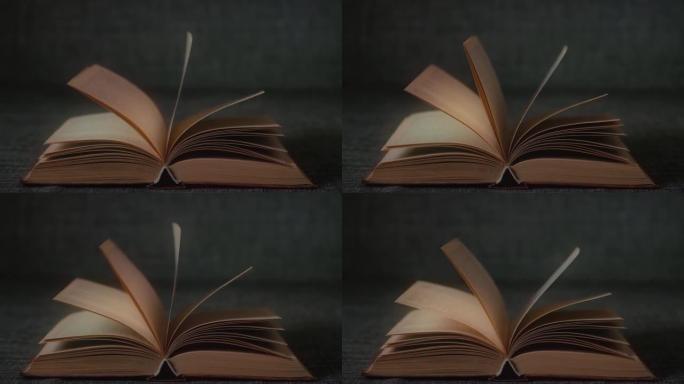 在黑暗的房间里，一本打开的书的书页随风飘动。慢动作