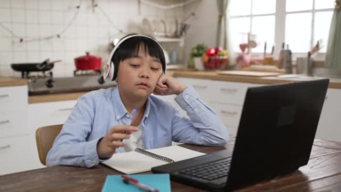 青少年亚洲韩国男孩对学习在线电子学习感到无聊使用互联网戴着耳机，在家旋转笔。教育与知识现代技术理念