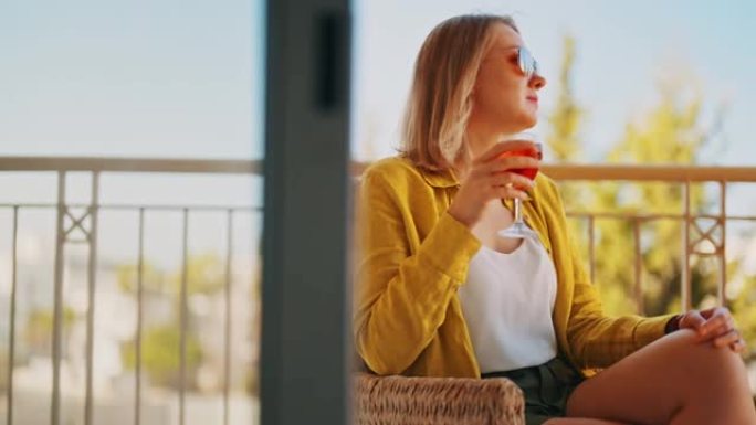 喝红酒的女人在阳台上享受假期。
