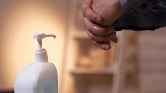 一个男人的手和洗手液的特写。