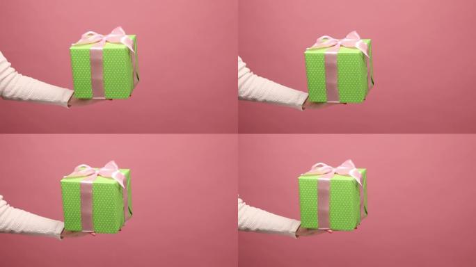 女人的手伸出带丝带的绿色礼品盒，在度假时赠送礼物。