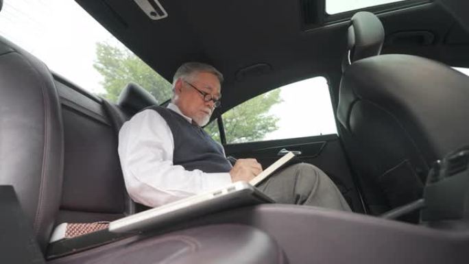 4k亚洲高级商人坐在汽车后座上写商业计划书