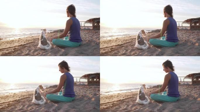 迷人的雄性和他的狗一起坐在sunruse的海滩上