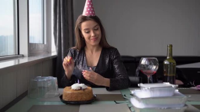高加索女孩在蛋糕上点燃蜡烛，在家过生日，孤独的女人用蛋糕庆祝周年，内向的检疫社交距离，生日庆祝