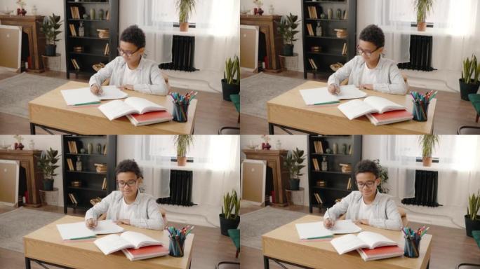 国内教育。快乐的非裔美国男孩在眼镜上做作业，在抄本中写作，跟踪镜头