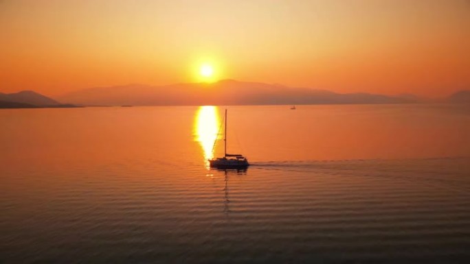 希腊爱奥尼亚海沿岸的日落。明亮的太阳，远处的陆地，漂浮的船，水中的倒影