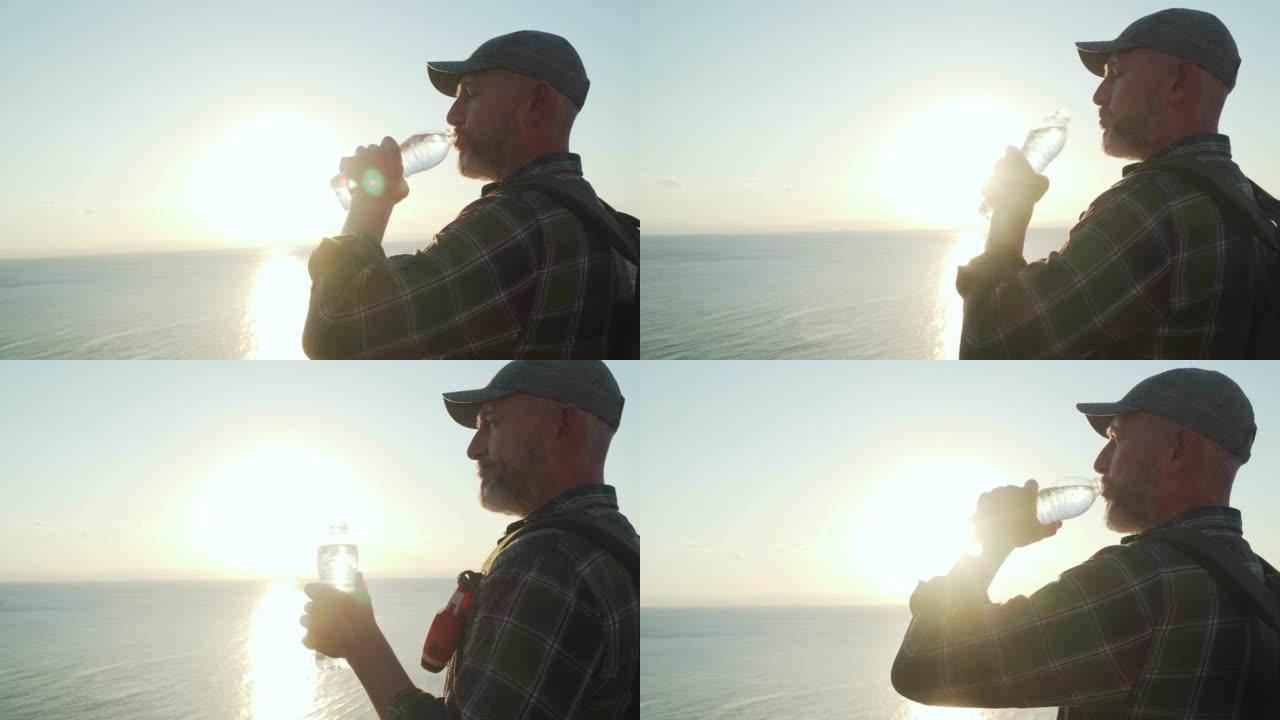 高级旅行者在海上日出前从瓶子里喝纯净水