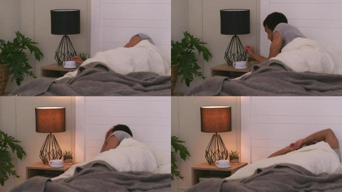 4k视频片段，一个年轻人打开床头灯并沮丧地躺在床上