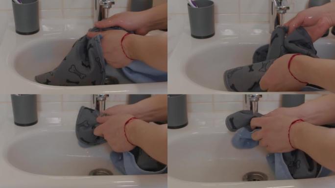 男性双手在水槽中清洗可重复使用的狗尿布