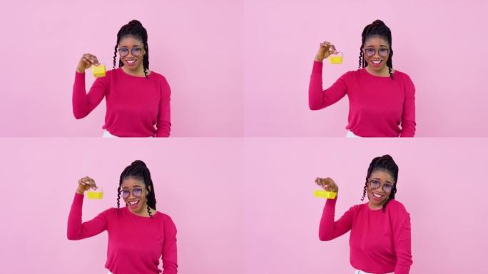 穿着粉色衣服的可爱开朗的年轻非洲裔美国女孩拿着一个迷你玩具购物篮。少女家庭主妇初学者站在坚实的粉红色