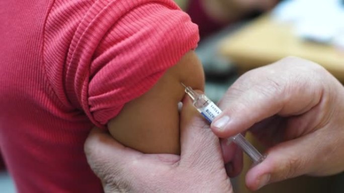 医生在孩子们的手中接种疫苗。在肩膀上注射注射器特写。4k