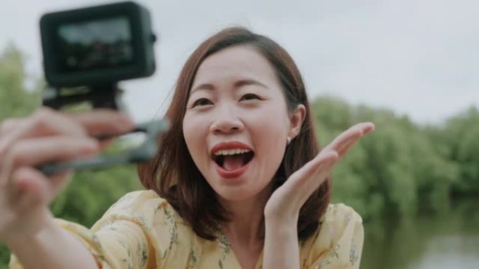 亚洲女人用GoPro相机自拍，背后有着美丽的自然。