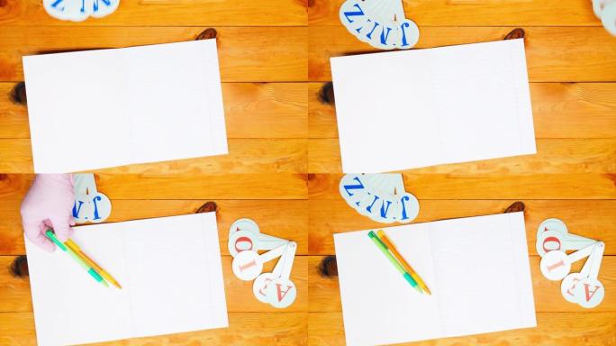 学校老师在学前班教室的木桌上排成一排的笔记本，彩色笔和字母，用于学习拼写。复制文本空间。广告的空白页