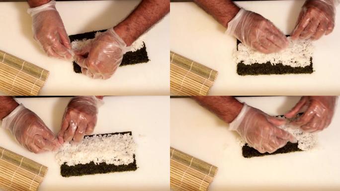 厨师将煮熟的寿司饭撒在海藻卷上 (紫菜)