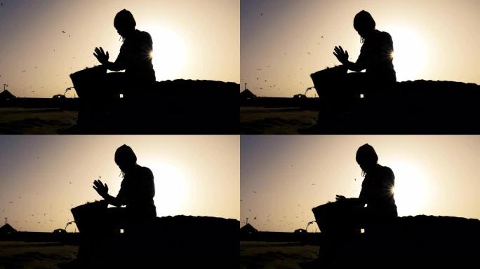 非洲打击乐，一个塞内加尔人的剪影在日落时分用他的手演奏传统的非洲鼓。