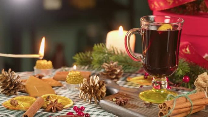 玻璃杯、谷胱甘肽和肉桂特写热酒。甜红葡萄酒配八角茴香，装饰松果点燃蜡烛。传统的冬季饮料。圣诞假期和新