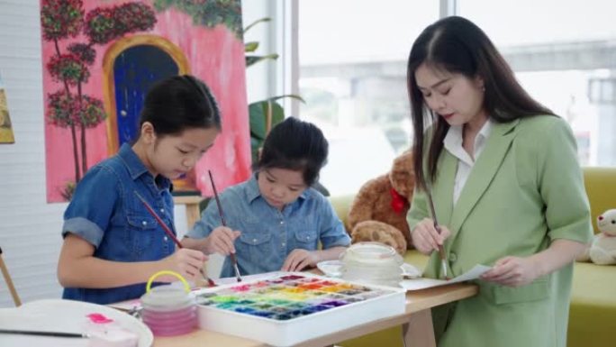 在一所艺术学校里，一位美丽的亚洲老师正在绘画课上教孩子们，教育的概念。