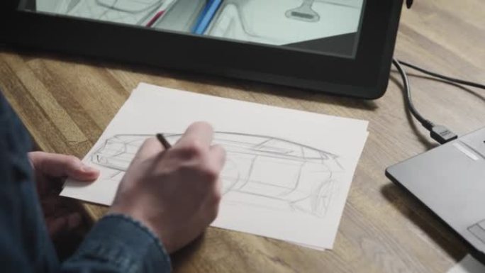 用铅笔在纸上画手的特写。设计师在一张纸上画了一辆新车。带设备的现代设计工作室