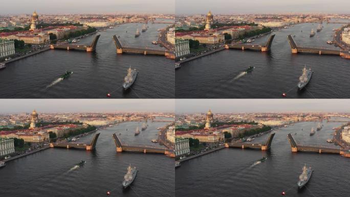 清晨，在俄罗斯海军节日之前，涅瓦河上的空中景象与军舰，军舰从一座升起的吊桥下通过，最新的巡洋舰在标志