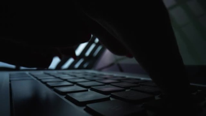 女人在黑暗中使用笔记本电脑在台式机上工作。女自由职业者在家庭办公室用键盘在笔记本上打字。键盘上女性手