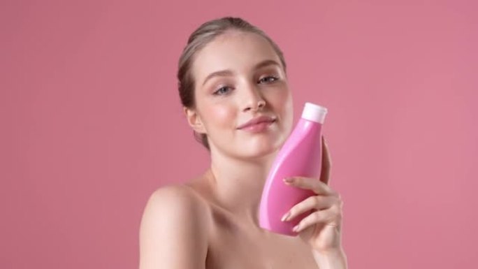 一个高兴的年轻女子正拿着一个粉红色的瓶子摆姿势