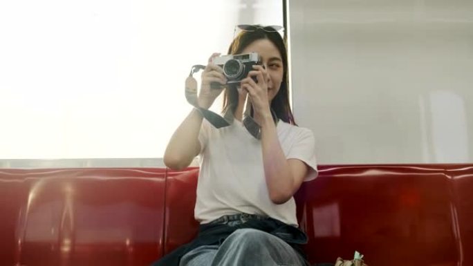 乘火车旅行的亚洲女性游客，用胶片相机拍摄快照照片。