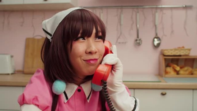 快乐迷人的亚洲女角色扮演者在固定电话上交谈的肖像