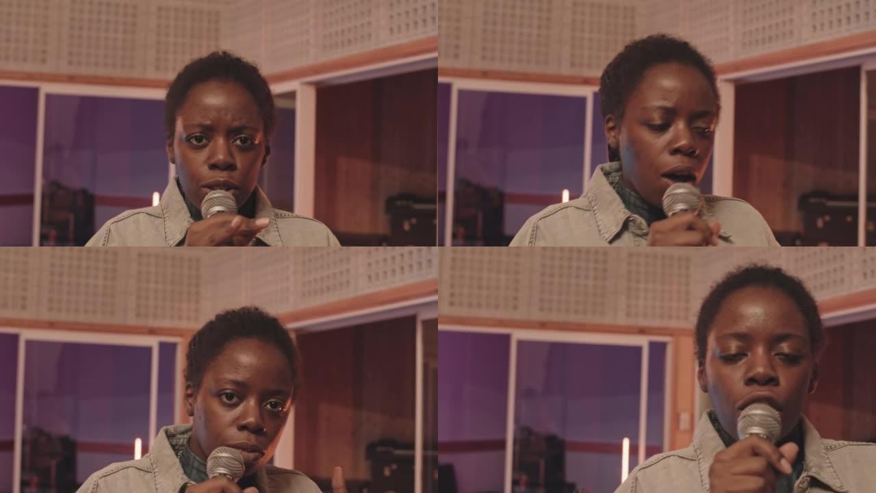年轻的黑人妇女在演播室的麦克风中唱歌