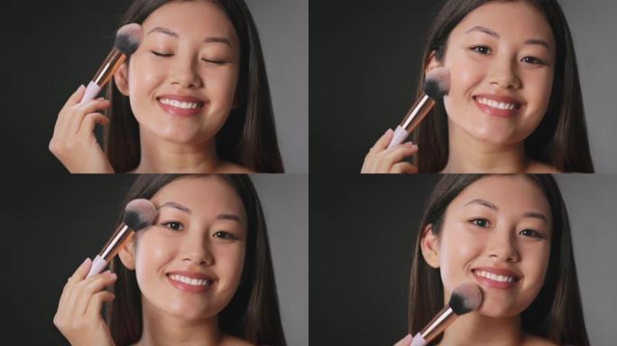 完美的外观。年轻美丽的亚洲女人自己化妆，用专业化妆刷涂抹胭脂