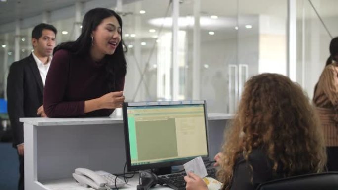 微笑的白人女性航空公司工作人员使用计算机并在机场的登机柜台工作