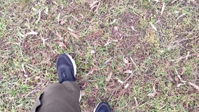 男人走在秋天的草地上，第一人称视角，双腿自上而下的视角