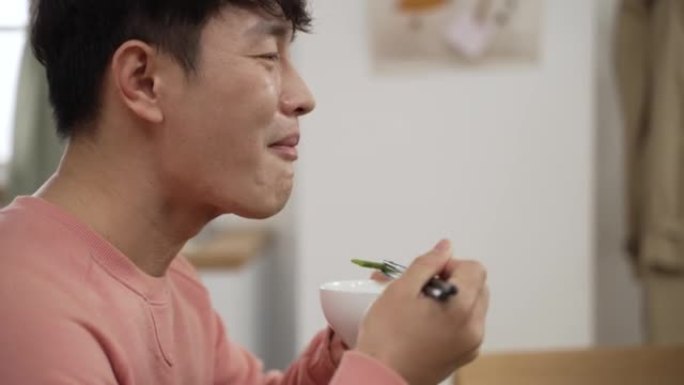侧视头像微笑的亚洲男子吃着美味的食物用碗筷在家感受幸福