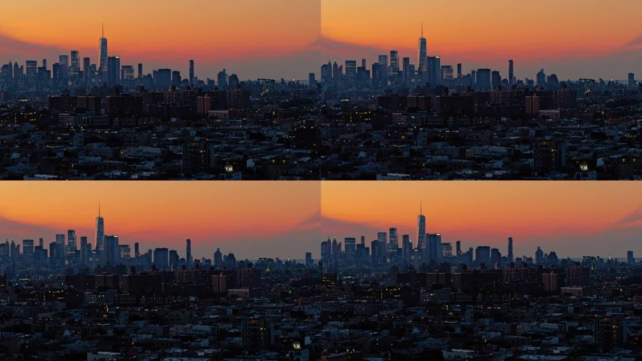 曼哈顿市区和自由塔上空的戏剧性天空在夜晚照亮。日落时分，可以看到布鲁克林住宅区的远景。具有宽轨道平移
