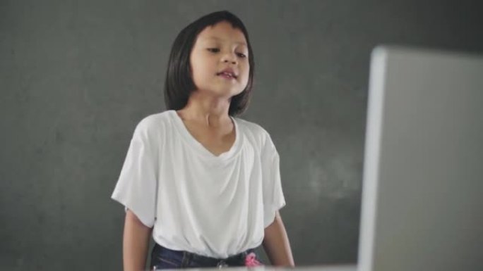 小女孩在家里唱歌看笔记本电脑。