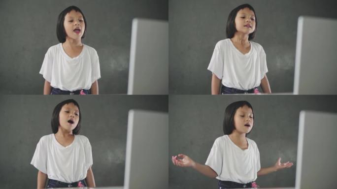小女孩在家里唱歌看笔记本电脑。