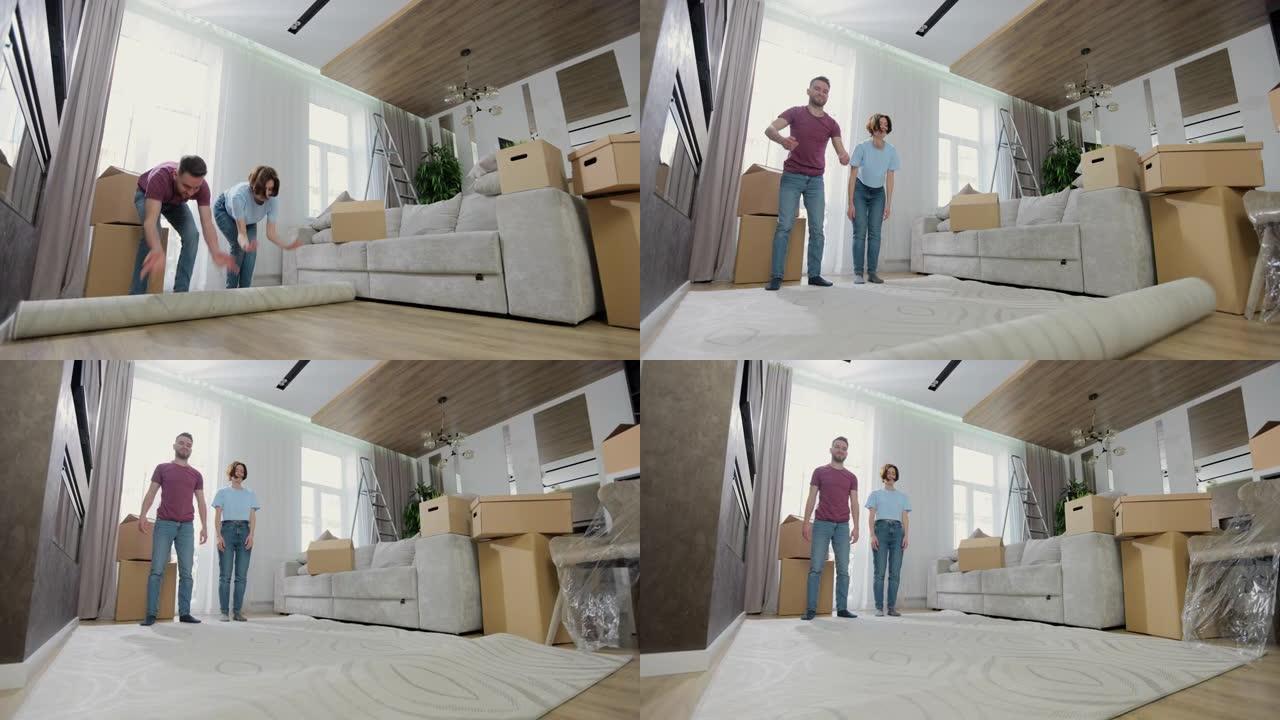 年轻的高加索夫妇在新公寓的客厅铺上地毯。夫妇在搬进新公寓时放垫子。