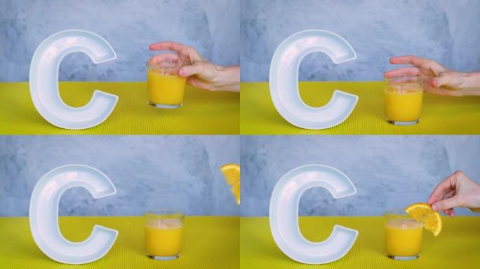食品概念中的抗坏血酸或维生素c。人的手将玻璃和鲜榨橙汁放在灰色和黄色背景上的大陶瓷字母C附近。