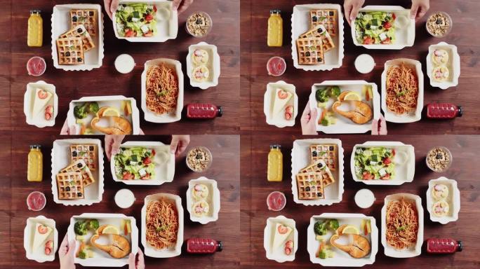 食品配送顶视图。将午餐盒放入煮熟的鲑鱼鱼和西兰花以及蔬菜沙拉中，将餐点放在木制桌子上的一次性容器中。