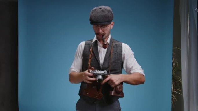 近距离的老式摄影师戴着眼镜和复古西装与老式机械胶片相机的快门手势与他的手和排队的人在工作室的合影