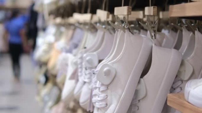 许多白鞋在时尚时尚的大众市场商店中连续悬挂，廉价的鞋类正在出售。鞋店有日常使用的简单鞋子，不同尺寸的
