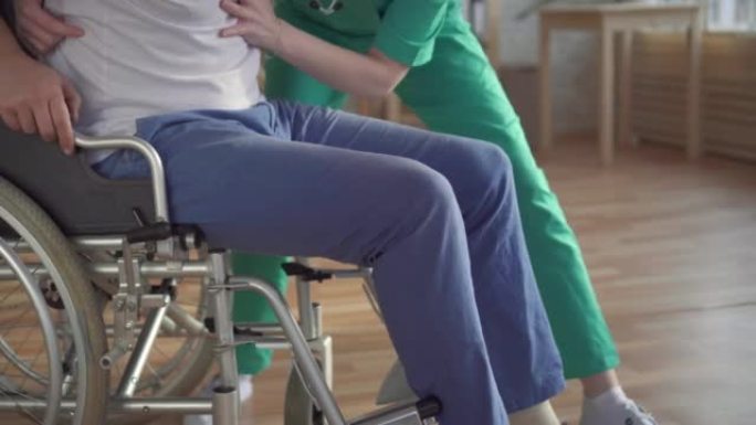 特写女护士在现代诊所帮助残疾人从轮椅上站起来