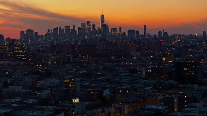 曼哈顿市中心和自由塔在夜晚照亮。日落时分，布鲁克林住宅区的远处景色，天空充满戏剧性。摄像机慢速前进的