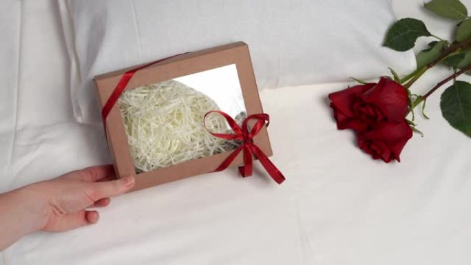 三朵红玫瑰和一盒白色床单上的礼物。