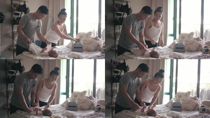 亚洲华人父母洗澡后为男婴涂乳液和更换婴儿服装