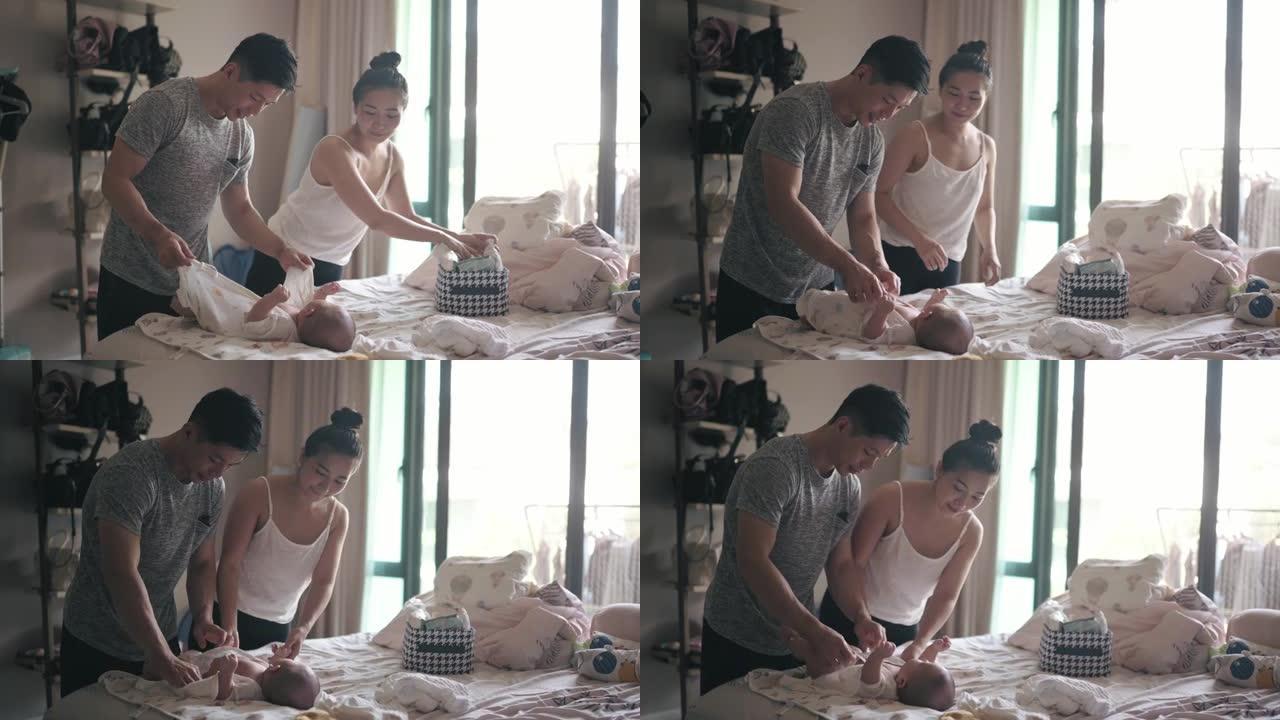 亚洲华人父母洗澡后为男婴涂乳液和更换婴儿服装
