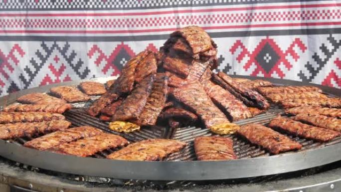 烤排骨在木炭大纺纱烤架上烤。街头美食节。油炸，不健康的食物