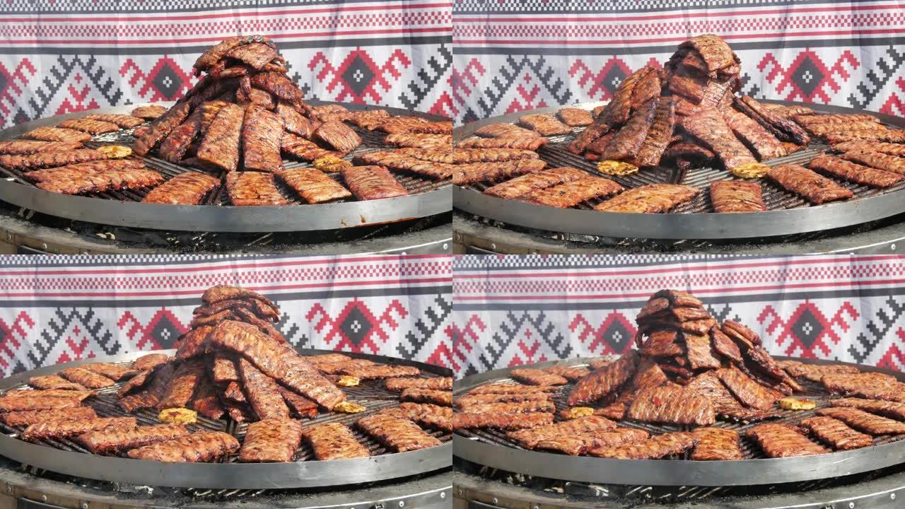 烤排骨在木炭大纺纱烤架上烤。街头美食节。油炸，不健康的食物