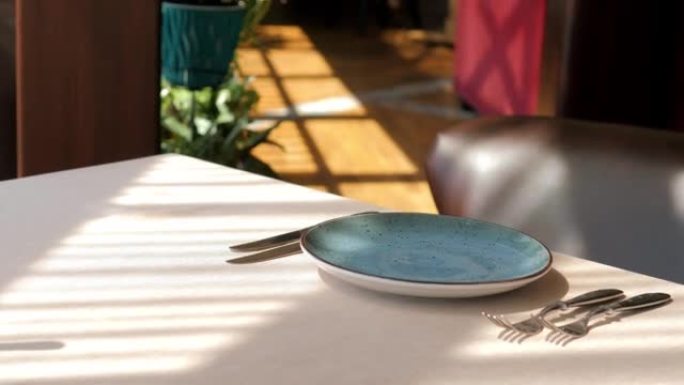 精英餐厅的餐桌设置特写。男人的手布置漂亮干净的空玻璃玻璃杯和盘子。装饰餐具和烛台。服务员摆桌子