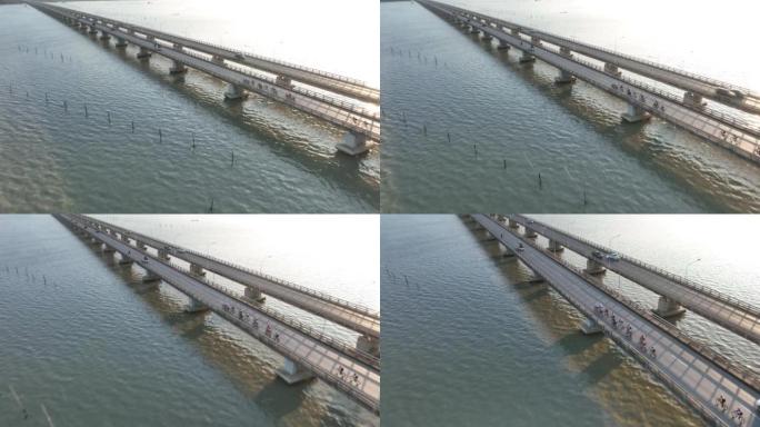 日出场景空中无人机在泰国宋卡省宋卡河的桥上拍摄了大批自行车骑行
