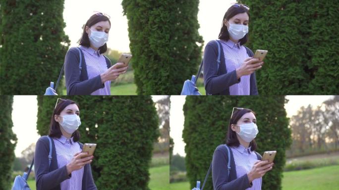 脸上戴着保护性医用口罩的可爱女孩去公园用手机，慢动作